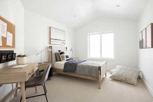 Carpeted bedroom with lofted ceiling and an office area