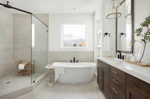 Full bath featuring a freestanding bath, a walk in shower, tile walls, vanity, and light tile patterned floors