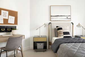 Carpeted bedroom featuring baseboards and an office area
