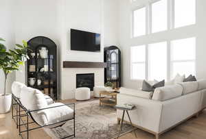 Living room with wood finished floors, a tile fireplace, and a high ceiling