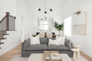 Living room featuring wood finished floors, stairs, and high vaulted ceiling