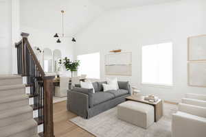 Living room featuring stairway, wood finished floors, and high vaulted ceiling