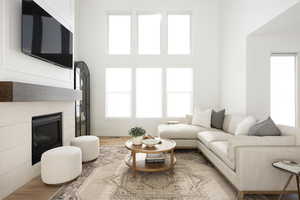 Living room with wood finished floors, a fireplace, and a high ceiling