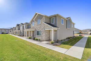 View of front facade with stone siding, a front lawn, stucco siding, and a residential view