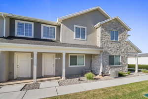 Traditional home featuring stone siding, stucco siding, covered porch, and roof with shingles