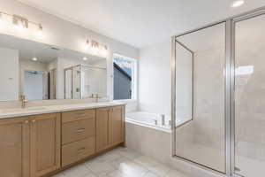 Full bathroom featuring a shower stall, double vanity, a garden tub, and recessed lighting