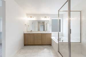 Full bath featuring a stall shower, a garden tub, double vanity, light marble finish flooring, and a closet