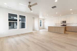 Kitchen with open floor plan, a center island with sink, light countertops, recessed lighting, and tasteful backsplash