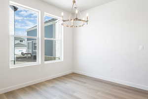 Unfurnished dining area featuring light wood-type flooring and a chandelier