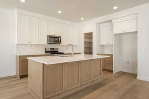 Kitchen with decorative backsplash, white cabinets, recessed lighting, appliances with stainless steel finishes, and light brown cabinets