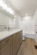 Full bathroom with vanity, washtub / shower combination, light wood-style flooring, and recessed lighting