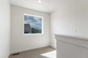 Spare room with baseboards and light colored carpet