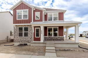 View of front facade with covered porch, a metal roof, and board and batten siding