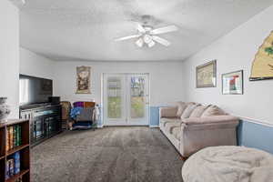 Living room with carpet flooring, a textured ceiling, and a ceiling fan