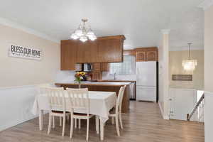 Dining space with a chandelier, light wood-type flooring, and crown molding