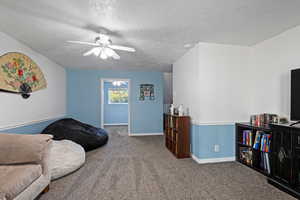Living room featuring carpet floors, a textured ceiling, and a ceiling fan