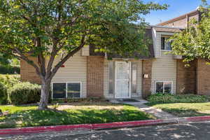 View of front facade featuring brick siding, a front yard, and mansard roof