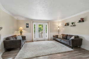 Living area with crown molding, light wood finished floors, and a textured ceiling