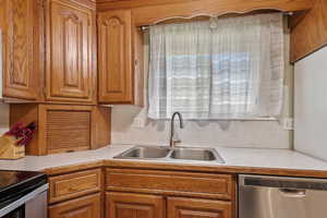 Kitchen with light countertops, appliances with stainless steel finishes, and brown cabinets