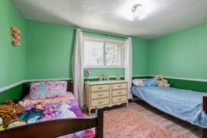 Bedroom with wood finished floors and a textured ceiling
