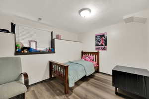 Bedroom with a textured ceiling and light wood-type flooring