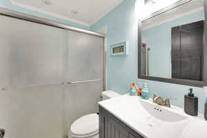 Bathroom with ornamental molding, vanity, and a shower stall