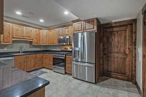 Kitchen featuring stainless steel appliances, recessed lighting, dark stone countertops, and brown cabinetry