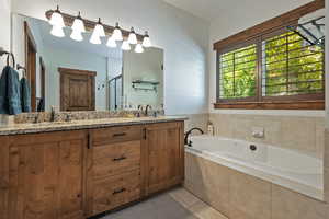 Full bath featuring double vanity, a garden tub, light tile patterned floors, and a shower stall