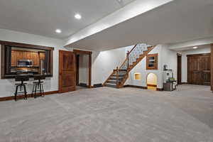 Unfurnished living room with recessed lighting, light carpet, and stairway