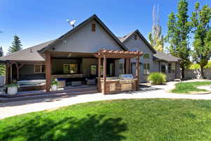 Back of property featuring exterior kitchen, a patio area, stucco siding, a hot tub, and a pergola