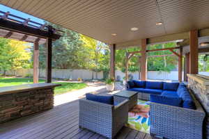 Wooden deck featuring a fenced backyard, an outdoor living space, and a pergola