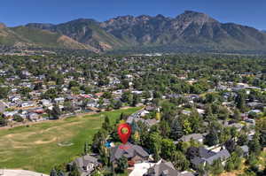 Aerial overview of property's location with nearby suburban area, a mountain backdrop, and a golf course