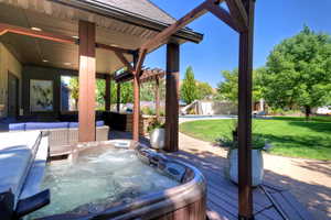 Wooden terrace featuring a hot tub, a pergola, and a patio