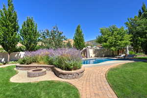 View of pool featuring a water slide, a patio area, a fenced backyard, and an outdoor fire pit