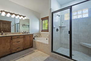 Full bath with a bath, a stall shower, double vanity, and light tile patterned flooring