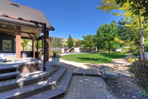 View of patio with a deck with mountain view and an outdoor hot tub