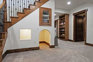 Stairway featuring carpet flooring, recessed lighting, and arched walkways