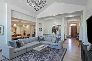 Living area featuring a chandelier, light wood-style floors, and high vaulted ceiling