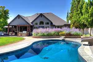 Outdoor pool with exterior kitchen, a patio area, a water slide, and a diving board