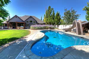 View of swimming pool with a patio, a water slide, and a diving board