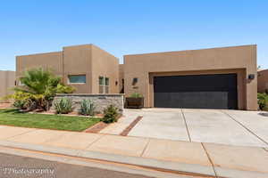Pueblo revival-style home with stucco siding, driveway, and an attached garage