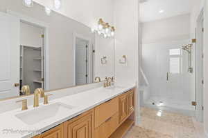 Bathroom with a shower stall, double vanity, light tile patterned floors, and a spacious closet