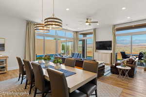 Dining room featuring light wood-style floors, floor to ceiling windows, a chandelier, plenty of natural light, and a ceiling fan