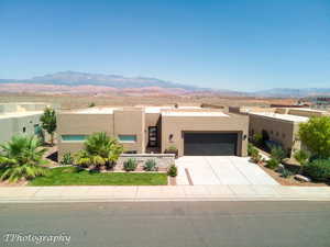Adobe home with stucco siding, a mountain view, an attached garage, and driveway