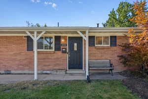 View of exterior entry with covered porch and brick siding