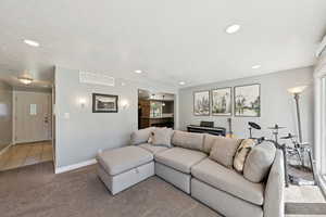 Carpeted living room with recessed lighting and tile patterned floors