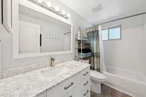 Bathroom featuring dark wood-style floors, shower / bathtub combination with curtain, and vanity