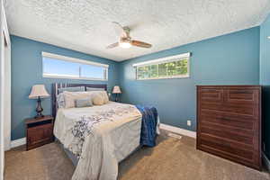 Bedroom with carpet floors, ceiling fan, and a textured ceiling