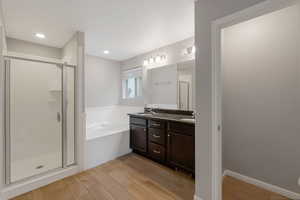 Full bath with a garden tub, double vanity, a shower stall, and light wood-style floors