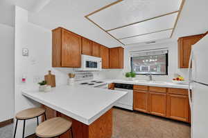 Virtually staged kitchen featuring warm cabinetry, peninsula bar, and light countertops